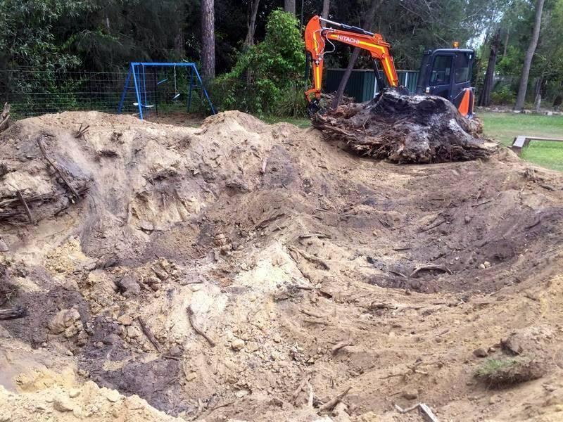Hitachi excavator removing a large tree stump